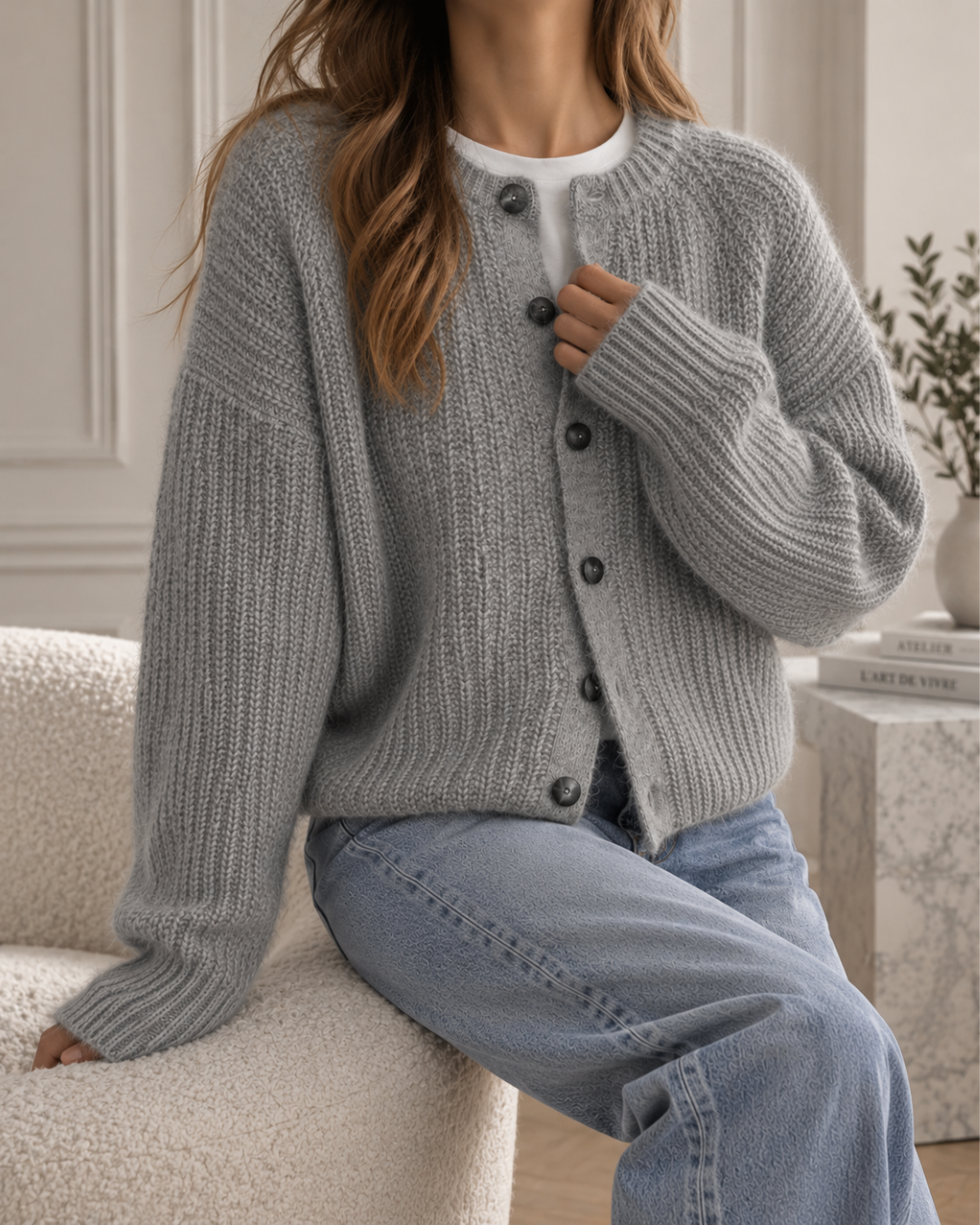 Cardigan femme gris en maille côtelée, coupe ample avec manches longues et fermeture à gros boutons noirs.