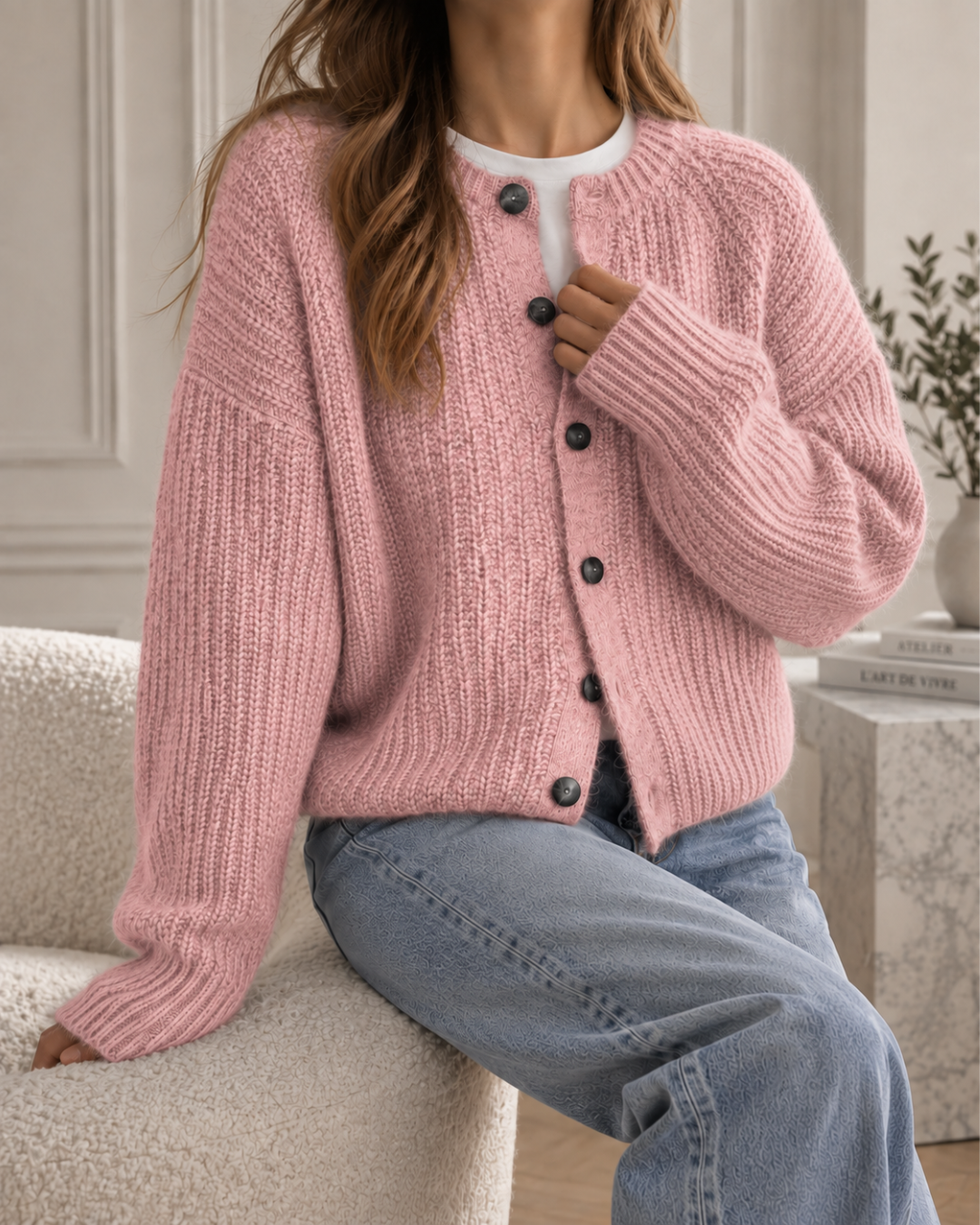 Cardigan femme rose en maille côtelée, coupe ample avec manches longues et fermeture à gros boutons noirs.