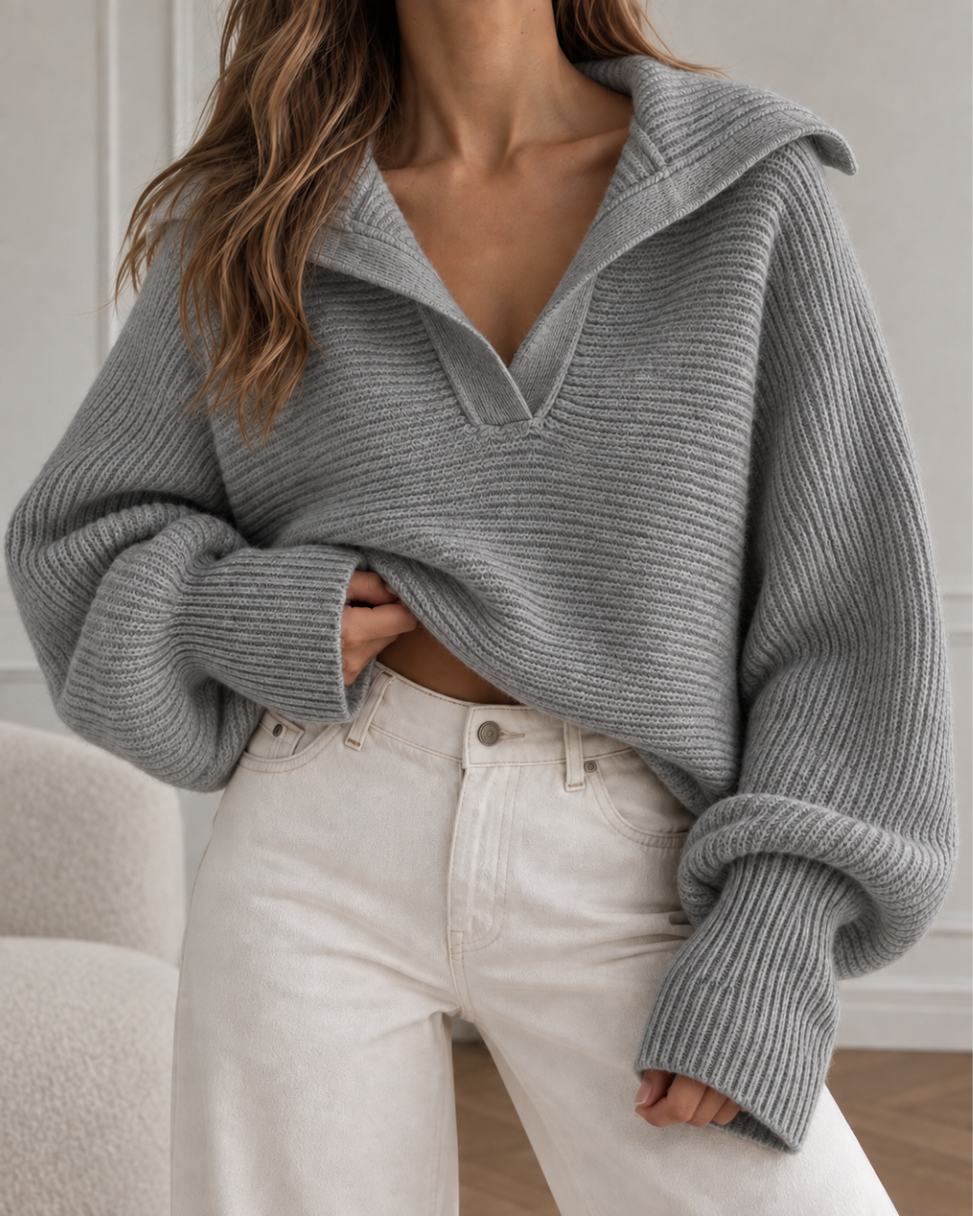 Pull oversize femme gris en maille côtelée, avec col large ouvert et manches longues amples.