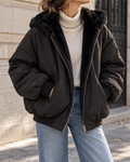 Bomber femme noir oversize avec capuche, doublure en fausse fourrure noire, fermeture zippée et manches longues.