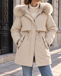 Parka femme beige à capuche avec bordure en fausse fourrure, coupe cintrée à taille ajustable, manches longues et poches zippées.