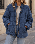 Veste matelassée femme bleu marine, coupe oversize avec col montant, manches longues, fermeture zippée et poches latérales.