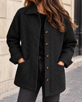 Veste matelassée noire pour femme, coupe droite avec col chemise, fermeture boutonnée et grandes poches plaquées.