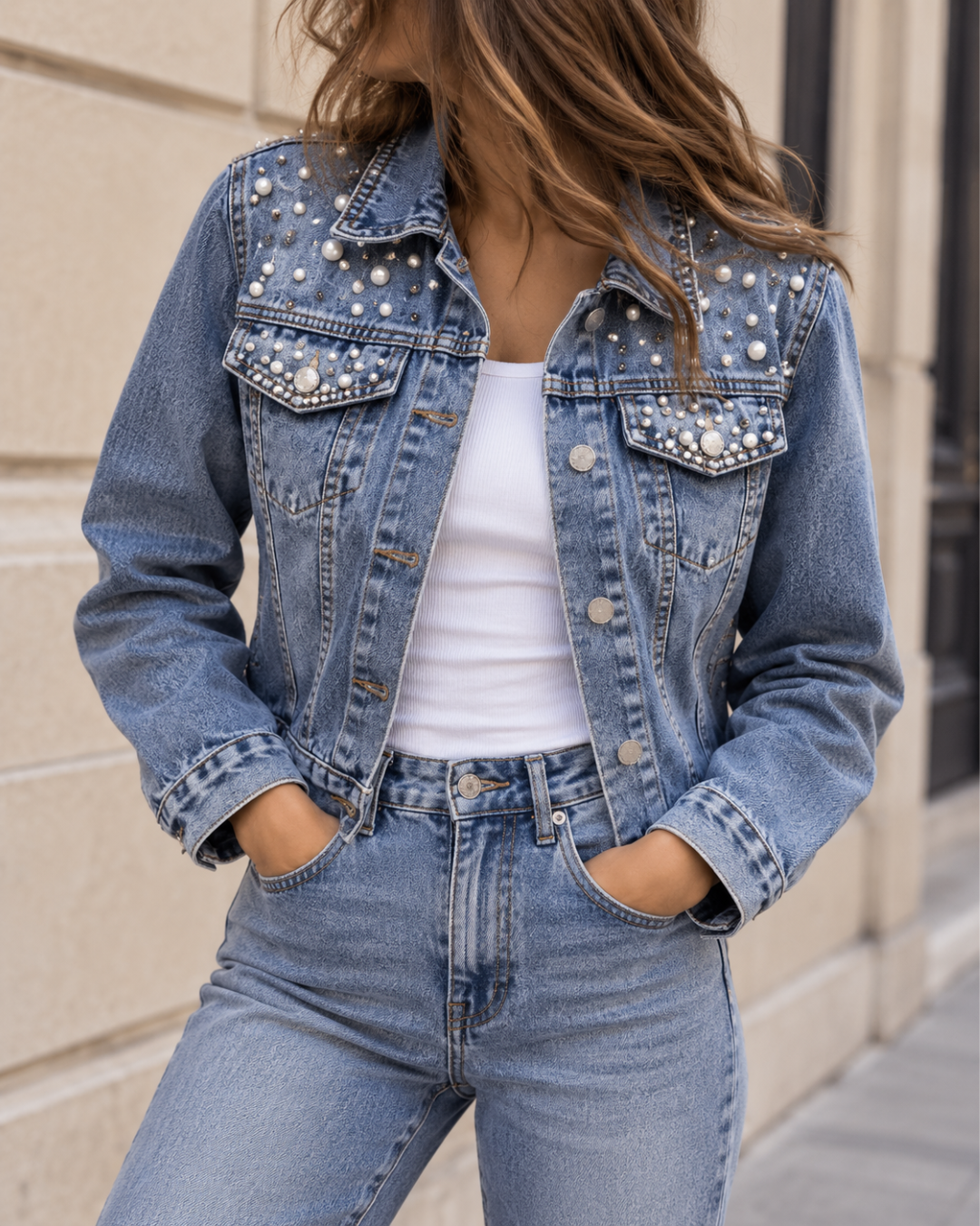 Veste en jean bleu pour femme, coupe courte avec boutons métalliques, poches poitrine et détails ornés de perles et strass.