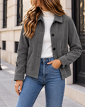 Veste courte en velours côtelé gris foncé pour femme, avec col classique, fermeture à boutons noirs et poches plaquées sur le devant.