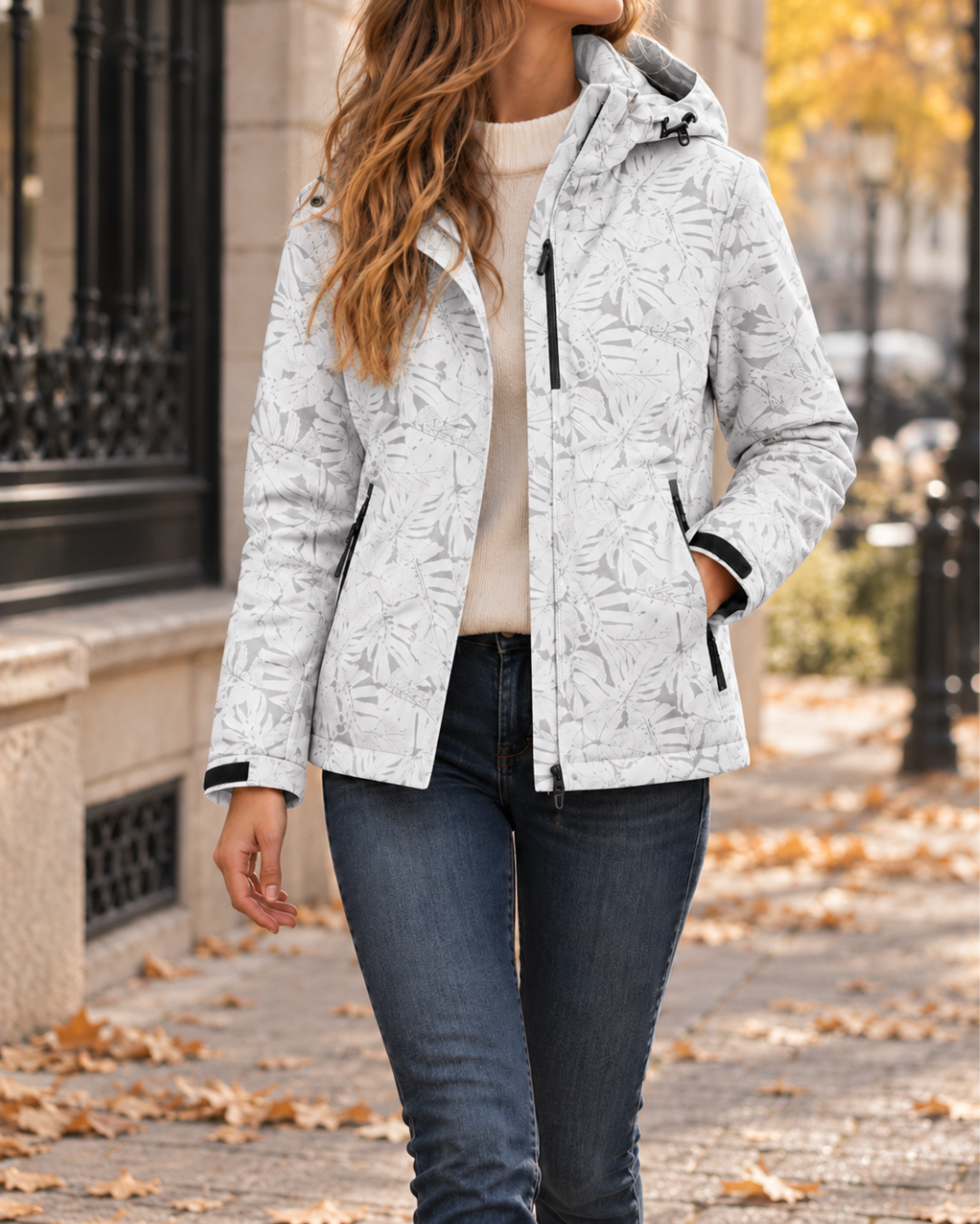 Veste femme ivoire à motif floral discret, avec capuche ajustable, fermeture zippée, manches longues et poches latérales zippées.