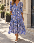 Robe longue fleurie femme bleue à col V, manches trois-quarts, taille ajustée, poches latérales et jupe évasée mi-mollet.